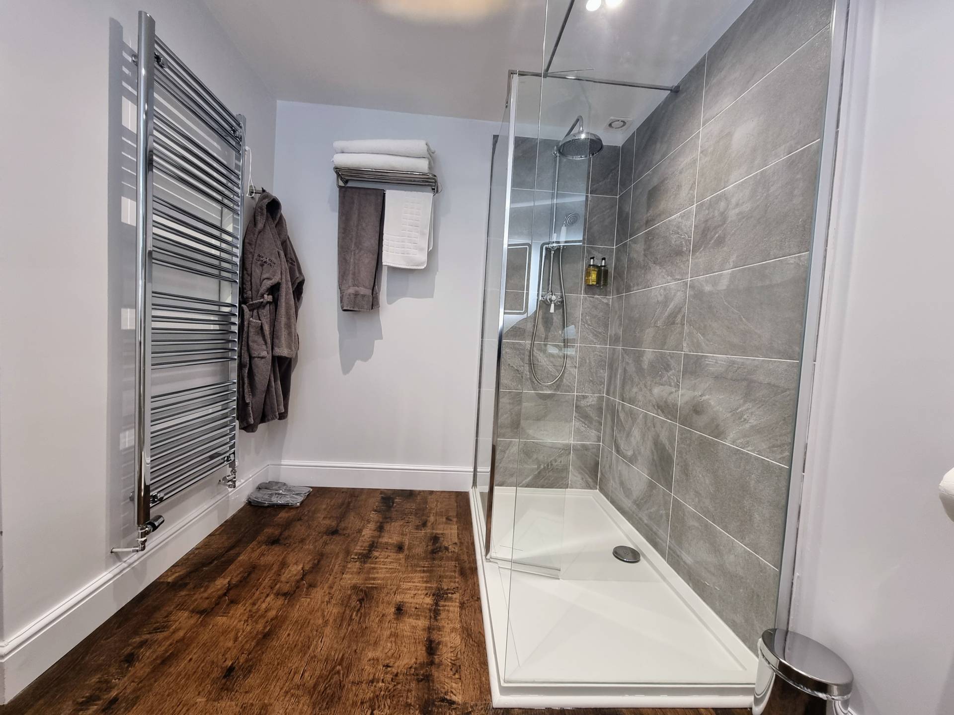 Walk-in non-slip shower with heated towel rail, towels and dressing gown in Suite 101 bathroom.