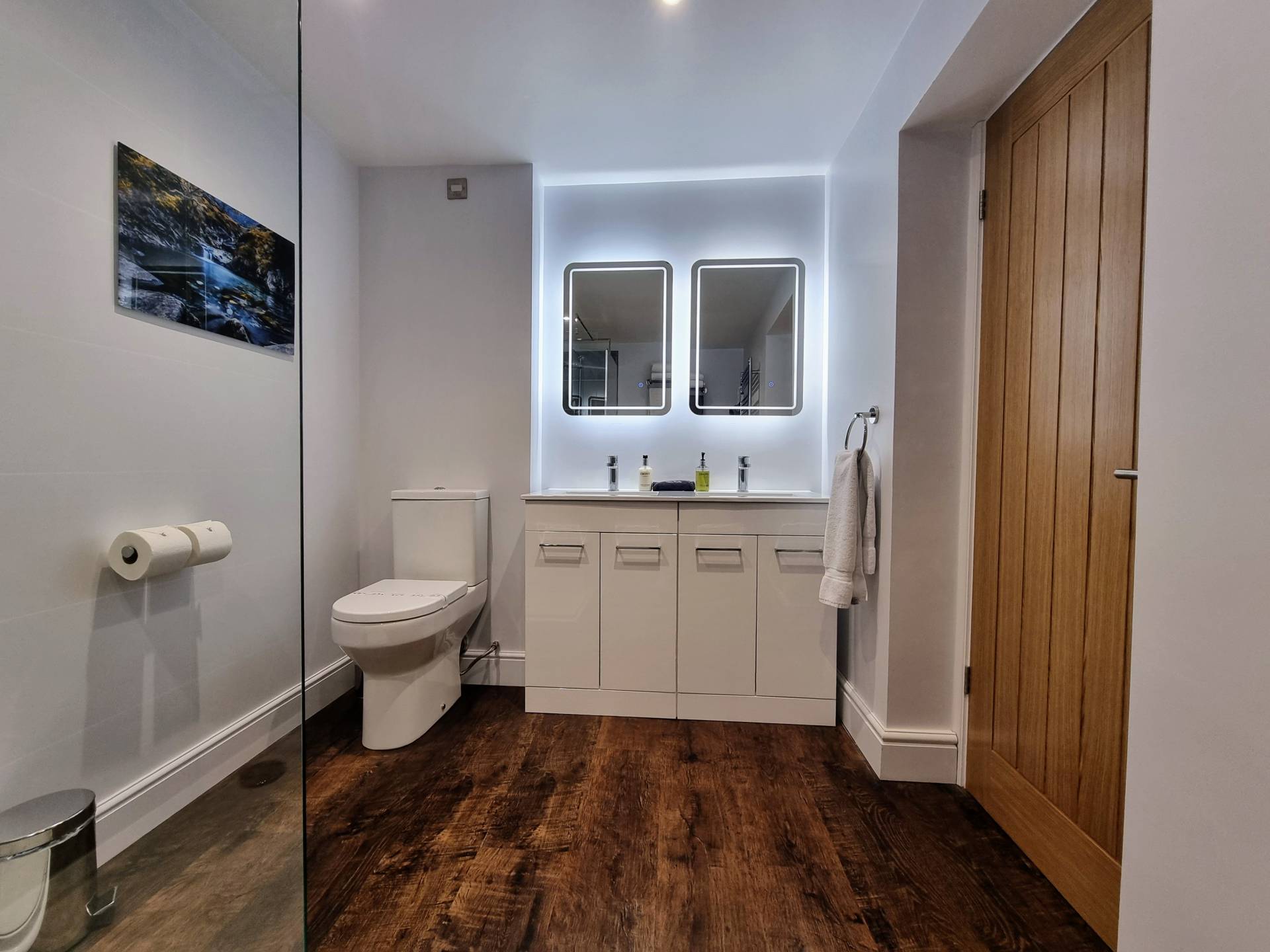 Luxury bathroom in Suite 101 with twin sinks, matching LED mirrors, comfort-height toilet and modern fittings.