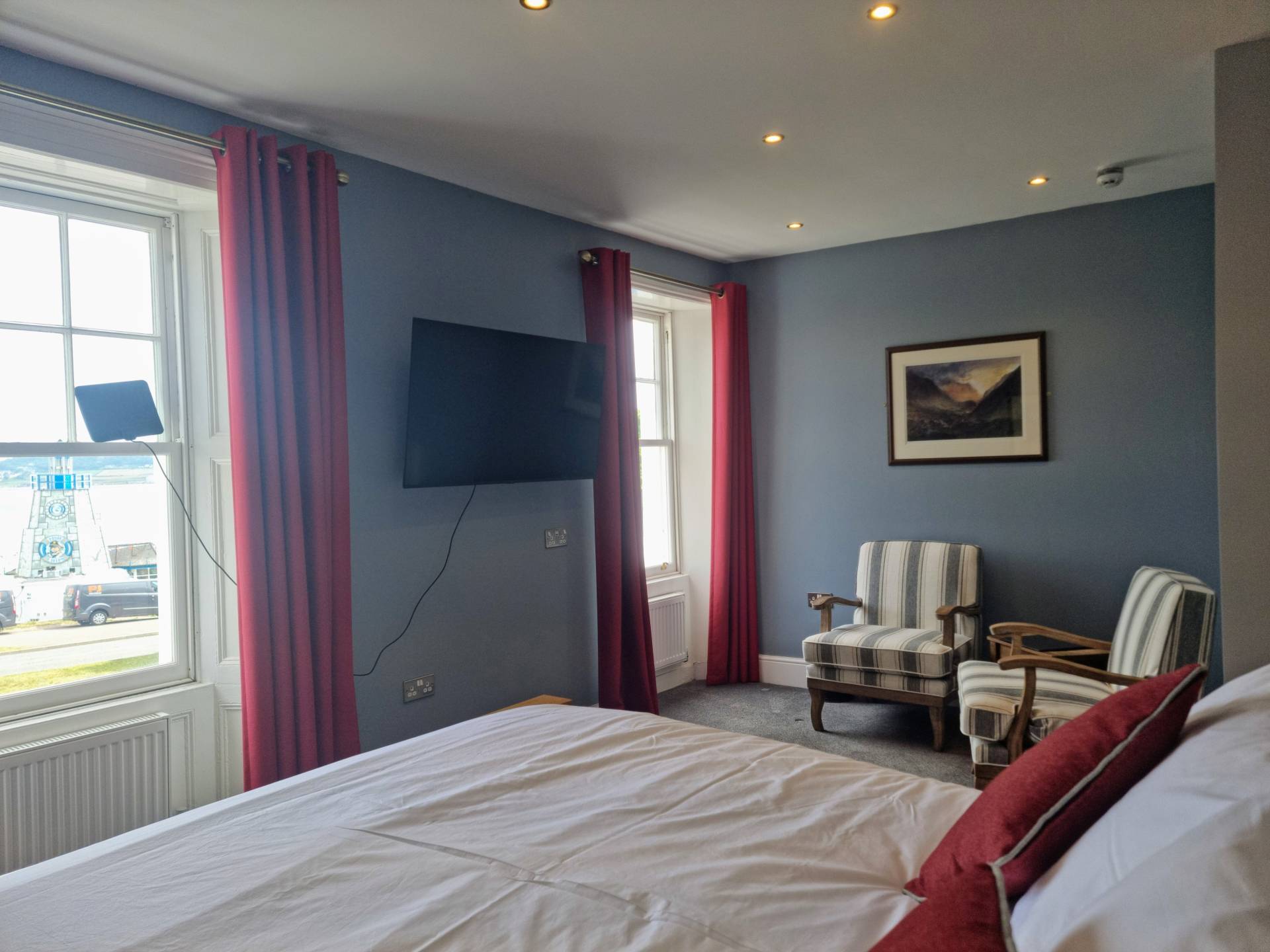 Super king bedroom with 50-inch Smart TV, seating area and sea views in Suite 103.