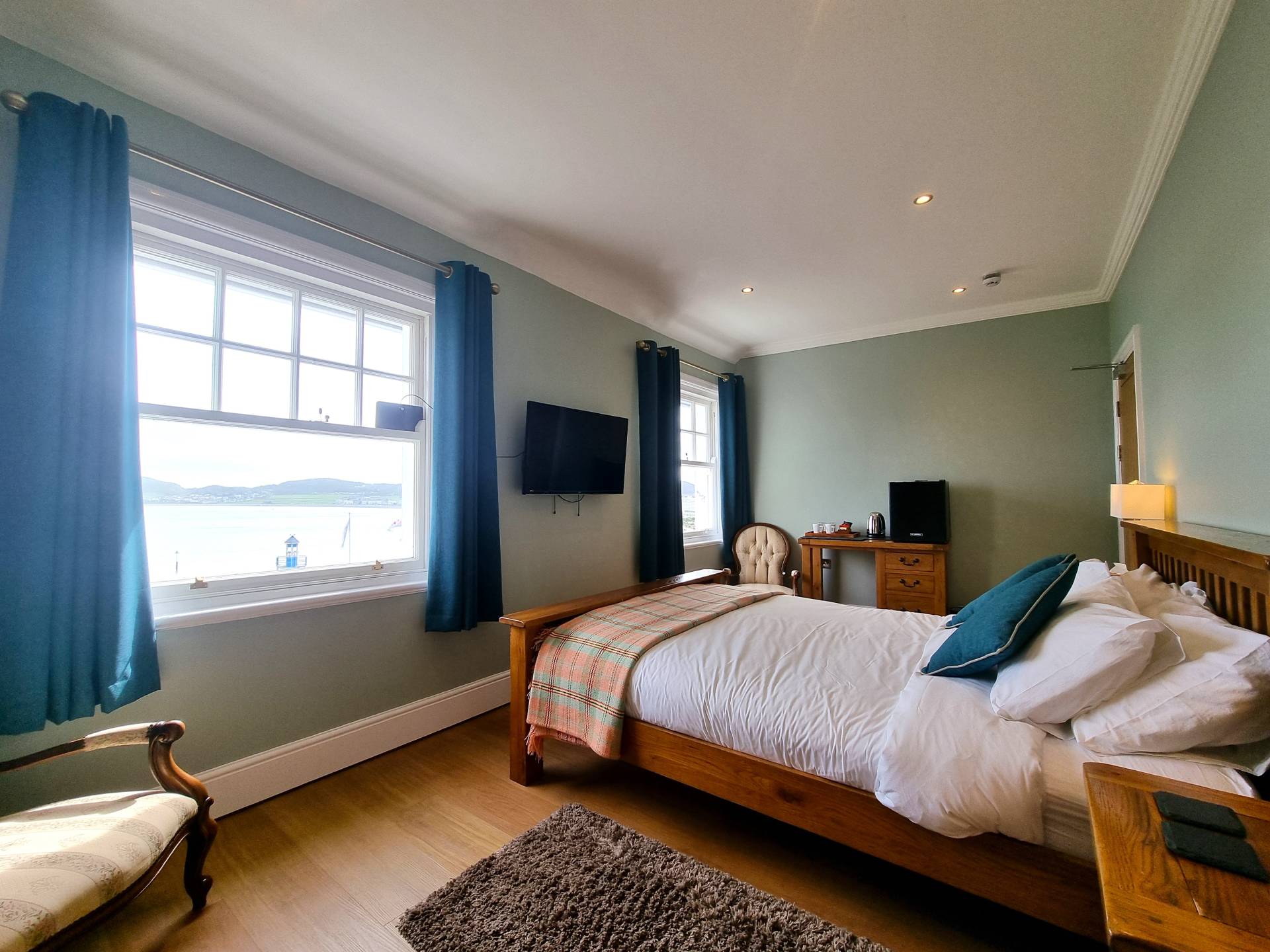 Room 301 at Min y Don Llandudno – luxury king bedroom with panoramic sea views from the bed and armchairs, fridge, and tea and coffee-making facilities.