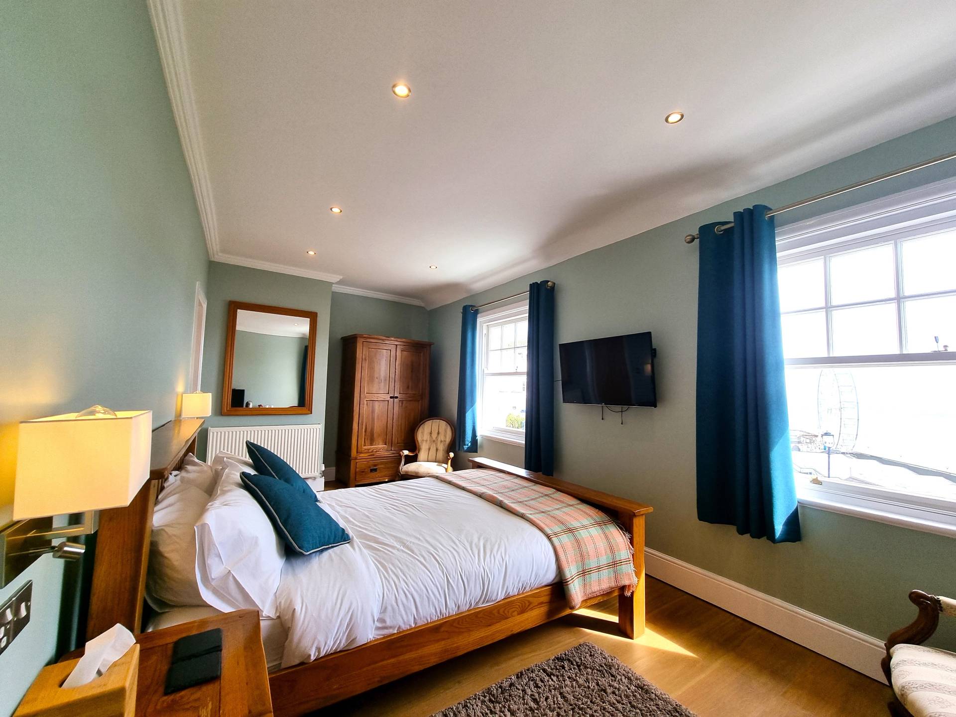Room 301 at Min y Don Llandudno – king-sized bed, TV with Netflix, wardrobe, and panoramic views including Llandudno Pier Wheel at night.
