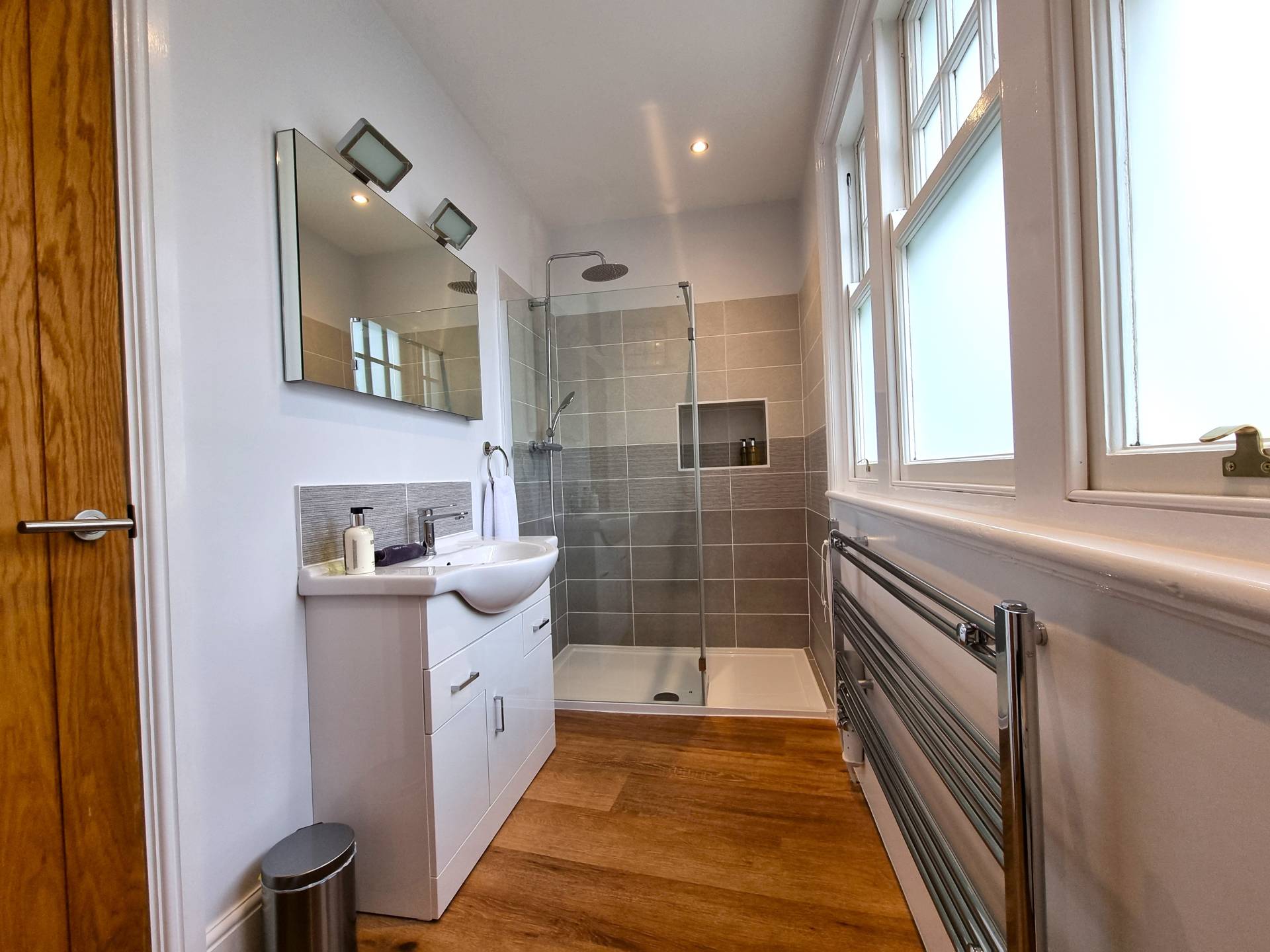 Luxurious en-suite bathroom in Suite 201 at Min y Don Llandudno with walk-in shower, heated mirror with shaving and toothbrush charging point, vanity unit, towel rail, makeup remover cloth, and complimentary toiletries.