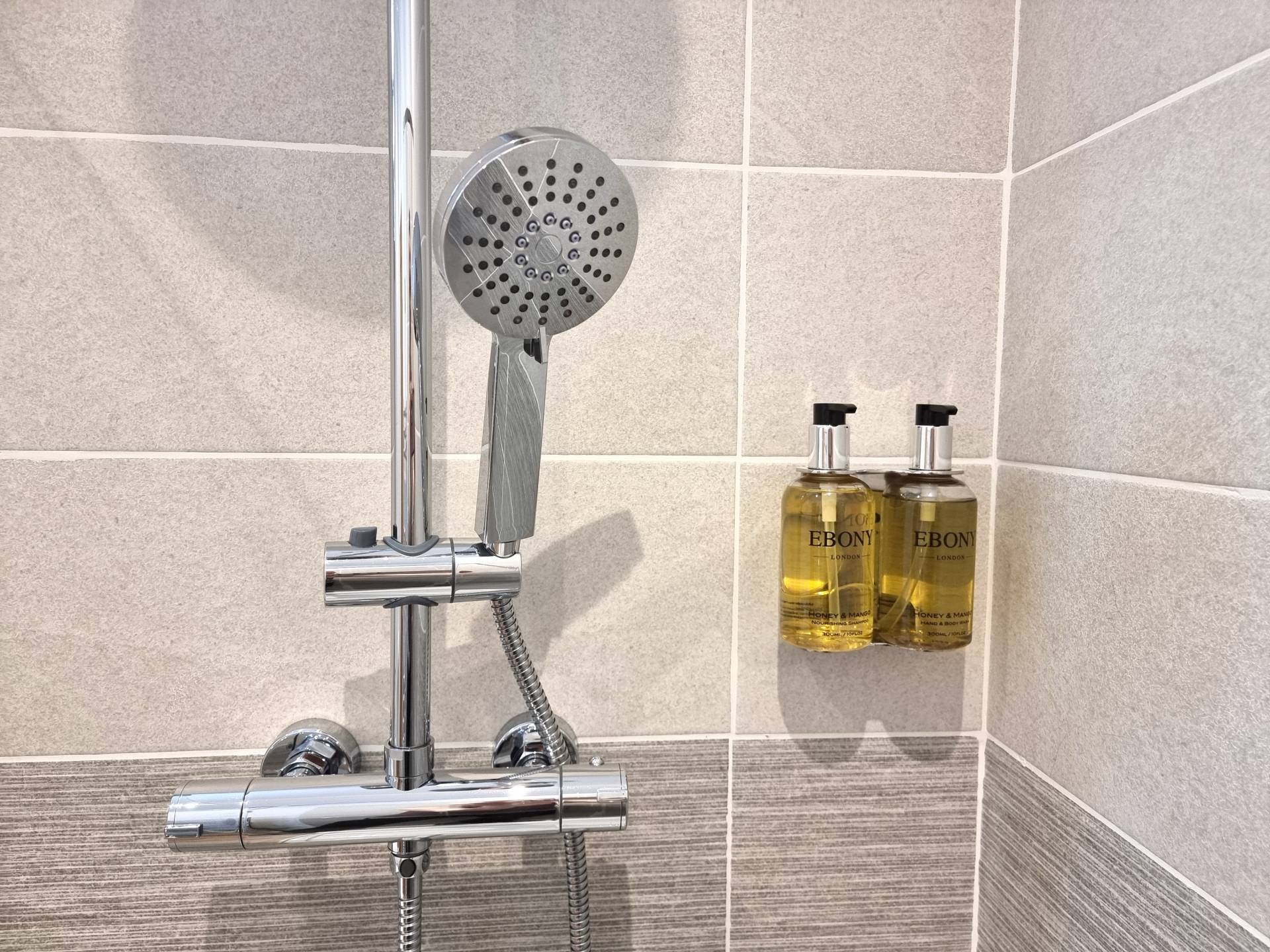 En-suite shower in Room 202 at Min y Don Llandudno with complimentary refillable shampoo, hand and body wash, and toiletries.